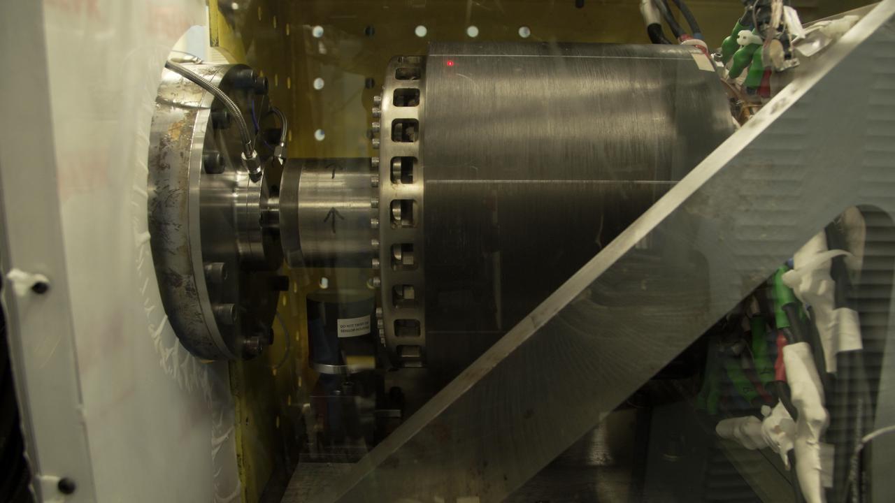 UIUC’s megawatt machine (right) was connected to a dynamometer (left) to test its effectiveness as an electric generator in a safety enclosure at a Collins Aerospace test facility in Rockford, Illinois. This unusual design has its rotating parts on the outside, so that both the cylinder on the right and the cylinder with arrows spin during operation.